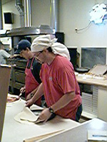 Employee tossing pizza crust in the air